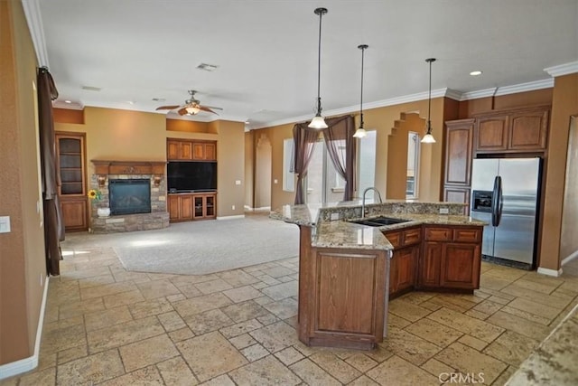 kitchen with stainless steel fridge, a kitchen island with sink, hanging light fixtures, and sink