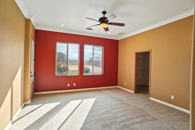 unfurnished bedroom featuring light carpet, crown molding, ceiling fan, a spacious closet, and a closet