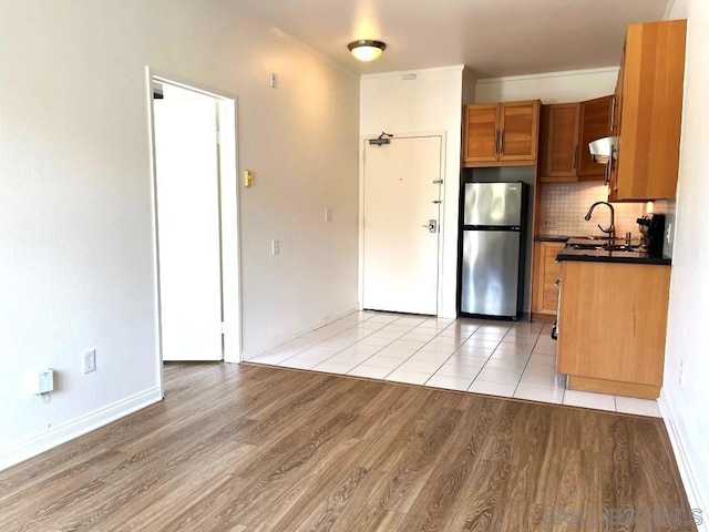 kitchen with backsplash, light hardwood / wood-style floors, and stainless steel refrigerator