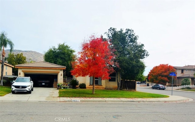 view of front facade featuring a mountain view, a front yard, and a garage