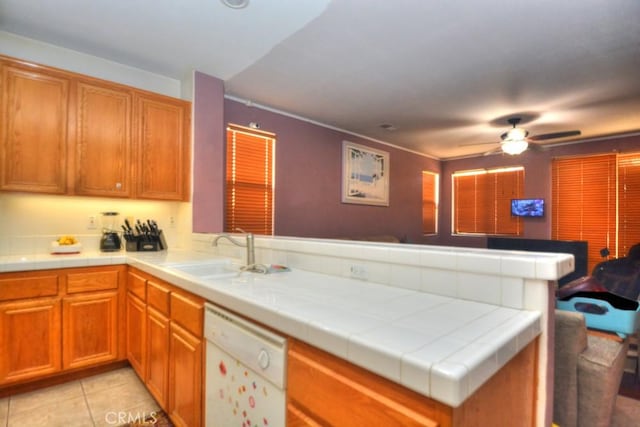 kitchen featuring tile countertops, kitchen peninsula, sink, white dishwasher, and light tile patterned floors