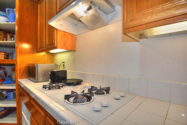 kitchen with tile counters, exhaust hood, and white gas cooktop