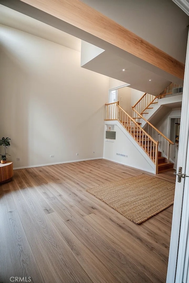 unfurnished living room featuring wood-type flooring and beamed ceiling