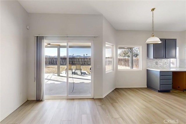 kitchen featuring light wood-type flooring, tasteful backsplash, and decorative light fixtures