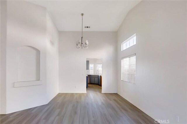 interior space with wood-type flooring, a high ceiling, and a chandelier