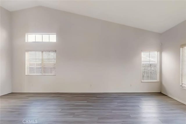 empty room with light hardwood / wood-style floors and vaulted ceiling