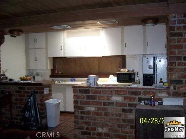 kitchen featuring black microwave, beamed ceiling, and white cabinets