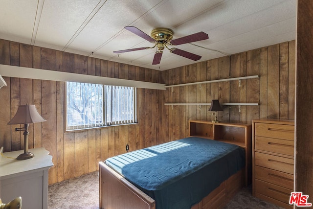 carpeted bedroom with ceiling fan and wooden walls