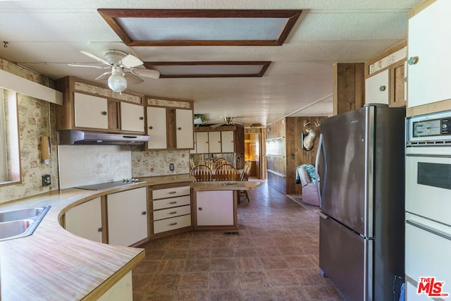 kitchen featuring white double oven, black electric stovetop, ceiling fan, white cabinetry, and stainless steel refrigerator