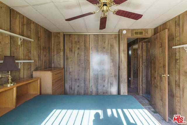 interior space featuring ceiling fan and wood walls