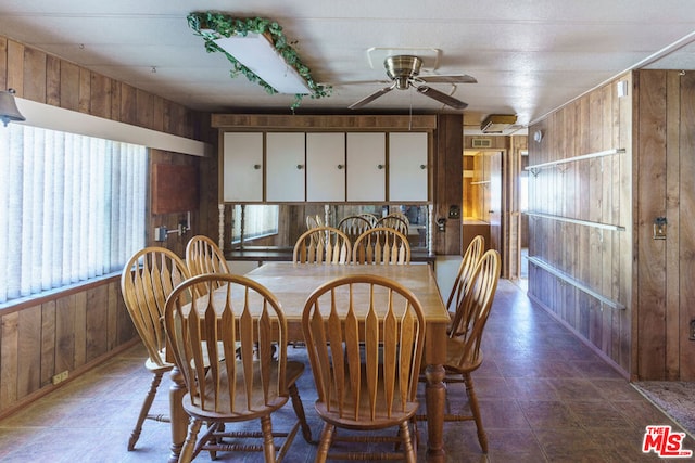 dining space with wood walls and ceiling fan