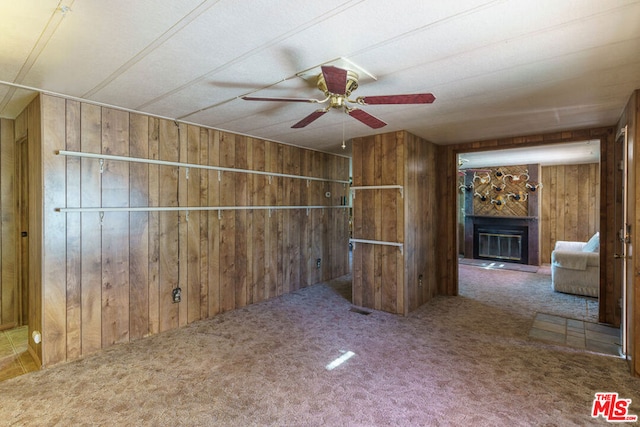 interior space with wood walls, carpet, and ceiling fan