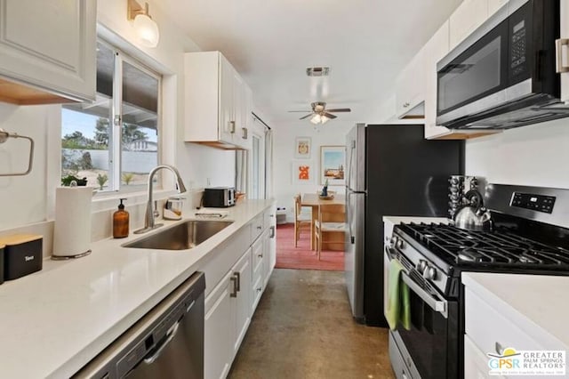 kitchen featuring appliances with stainless steel finishes, white cabinetry, ceiling fan, and sink