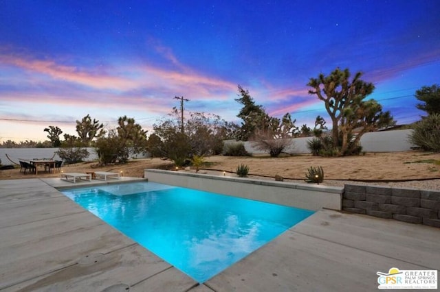 pool at dusk with a patio area