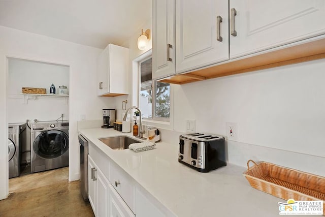 kitchen featuring washing machine and dryer, white cabinetry, sink, and dishwasher