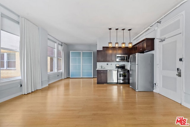 kitchen with decorative backsplash, dark brown cabinets, stainless steel appliances, pendant lighting, and light hardwood / wood-style floors