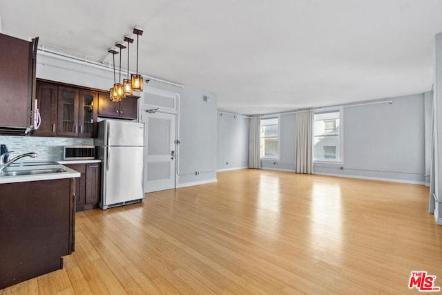 kitchen with backsplash, stainless steel appliances, sink, decorative light fixtures, and light hardwood / wood-style floors