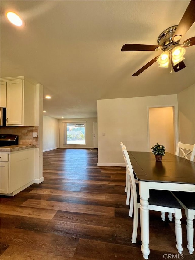 dining space with ceiling fan and dark wood-type flooring