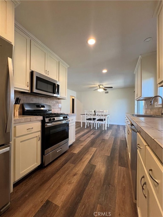 kitchen featuring sink, tile counters, dark hardwood / wood-style flooring, decorative backsplash, and appliances with stainless steel finishes