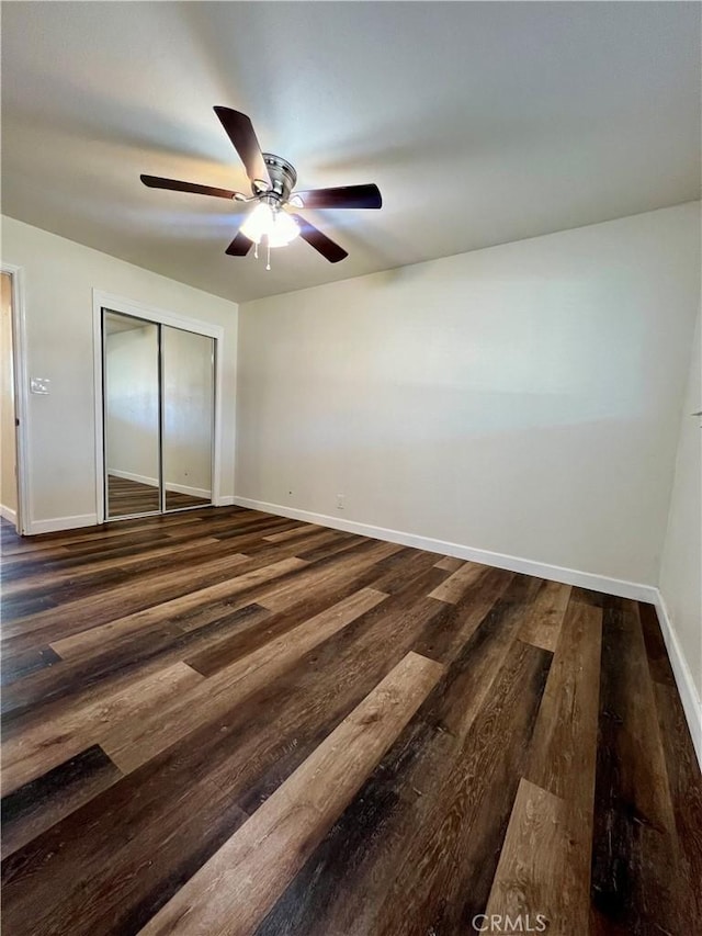 unfurnished bedroom with ceiling fan, a closet, and dark wood-type flooring