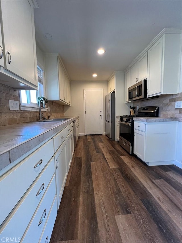 kitchen with white cabinetry, sink, stainless steel appliances, dark hardwood / wood-style flooring, and decorative backsplash