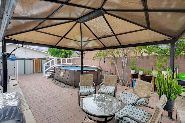 view of patio featuring a gazebo, a swimming pool, and a storage shed