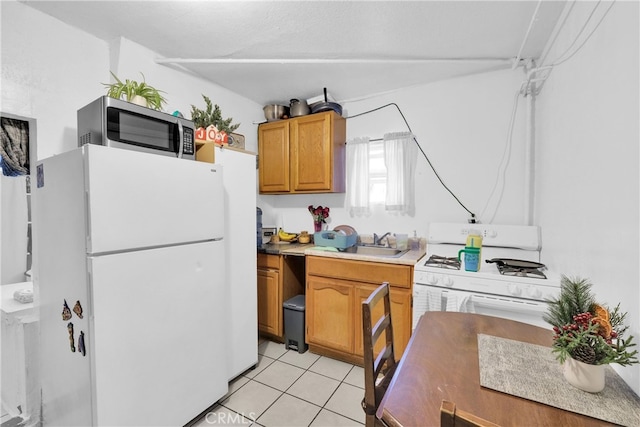 kitchen with sink, white appliances, a textured ceiling, and light tile patterned floors