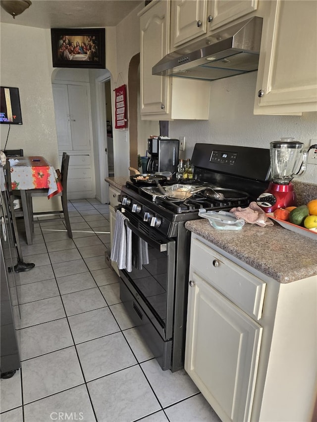 kitchen with gas stove, light tile patterned flooring, and cream cabinetry