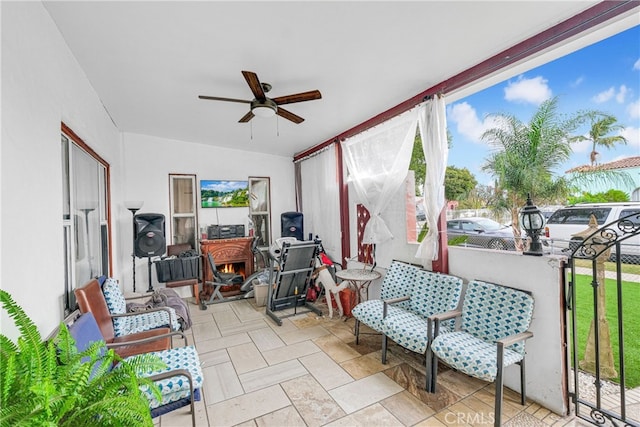 sunroom / solarium featuring ceiling fan and a wood stove