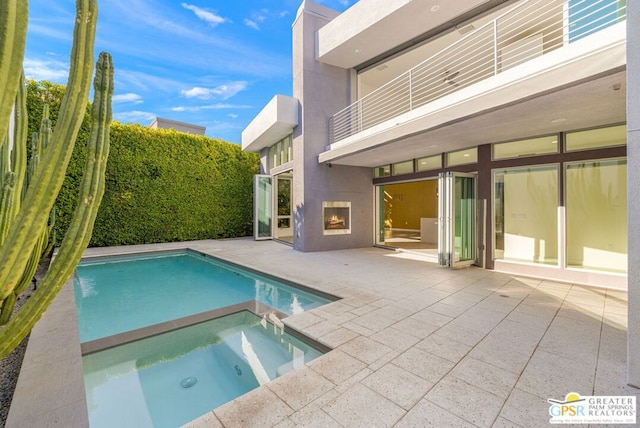 view of swimming pool featuring a patio area, an in ground hot tub, and exterior fireplace