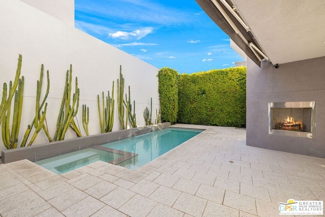 view of pool with an in ground hot tub, a patio, and an outdoor fireplace