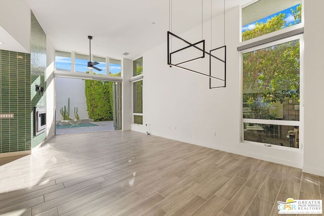 unfurnished living room featuring ceiling fan, expansive windows, and light hardwood / wood-style floors