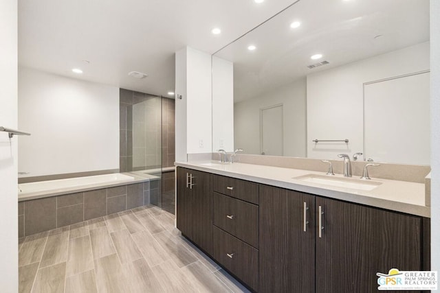 bathroom featuring plus walk in shower, hardwood / wood-style floors, and vanity