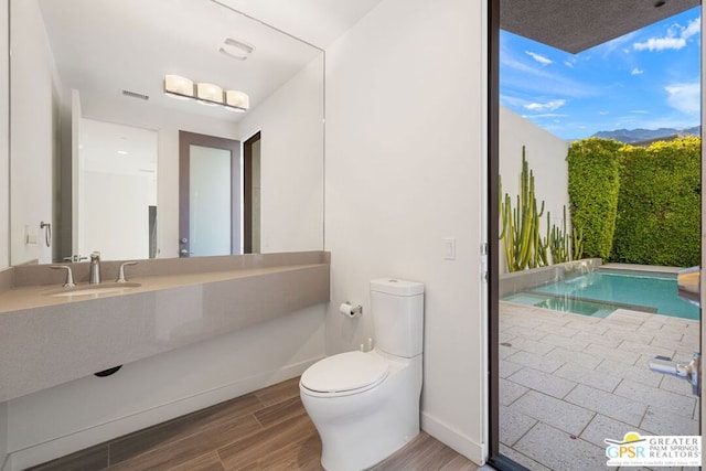 bathroom with hardwood / wood-style floors, toilet, and sink