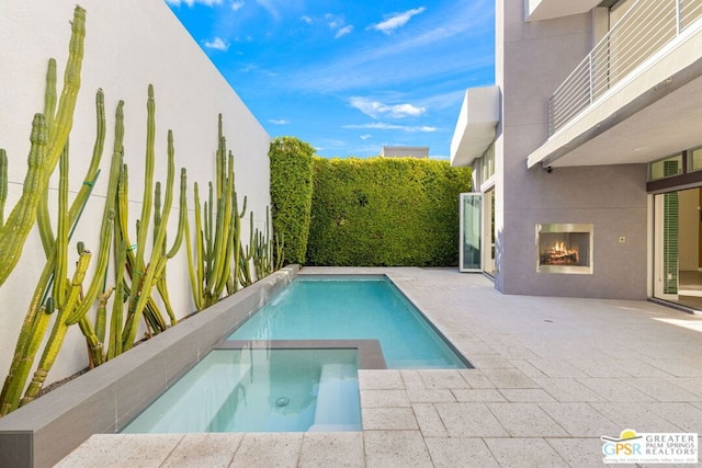 view of swimming pool featuring an outdoor fireplace, a patio area, and an in ground hot tub