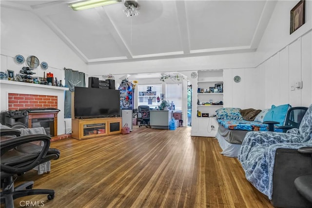 living room featuring hardwood / wood-style flooring, ceiling fan, a fireplace, and vaulted ceiling