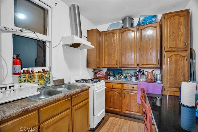 kitchen featuring light wood-type flooring, white gas range, and sink