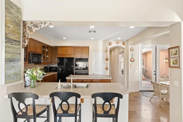 kitchen with kitchen peninsula, a kitchen breakfast bar, french doors, sink, and black appliances