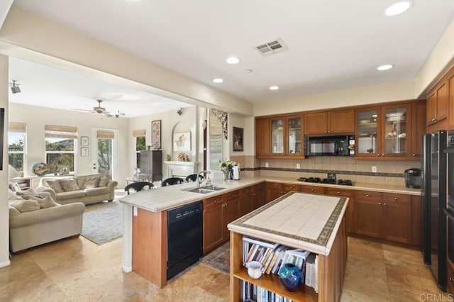 kitchen with decorative backsplash, ceiling fan, sink, black appliances, and a kitchen island