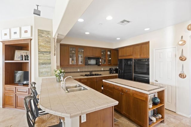 kitchen with black appliances, a kitchen breakfast bar, sink, decorative backsplash, and kitchen peninsula