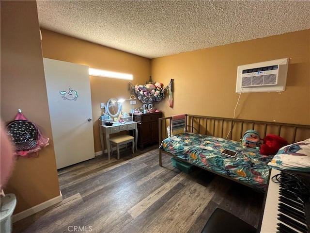bedroom with baseboards, a textured ceiling, a wall unit AC, and wood finished floors