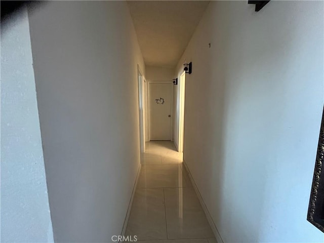 corridor with baseboards and light tile patterned floors