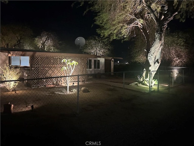 back of house at night featuring fence
