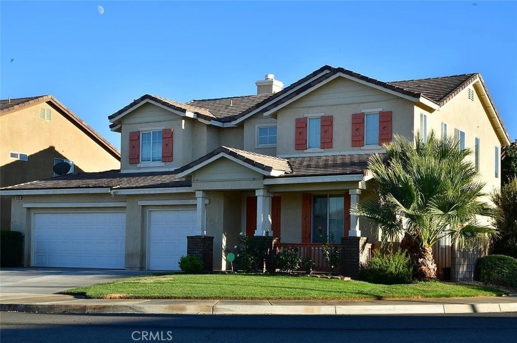 view of front of property featuring a porch, a garage, and a front lawn