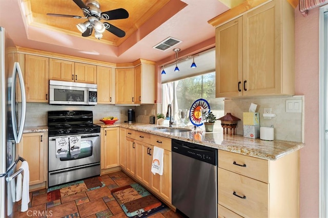 kitchen with light stone countertops, sink, stainless steel appliances, a raised ceiling, and decorative backsplash