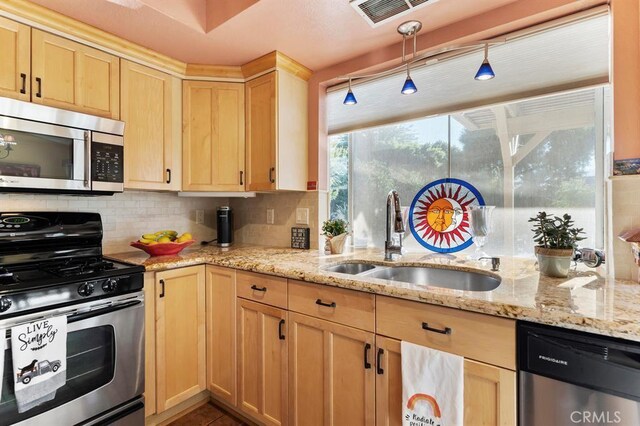 kitchen featuring light stone countertops, sink, stainless steel appliances, decorative backsplash, and light brown cabinetry