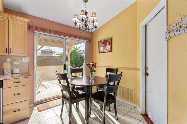 tiled dining space featuring a notable chandelier and vaulted ceiling