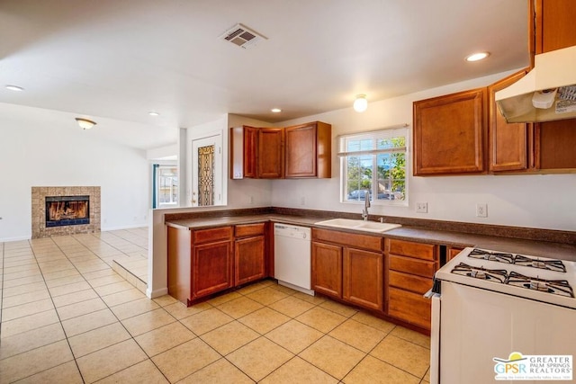 kitchen with white appliances, ventilation hood, sink, a tile fireplace, and light tile patterned floors