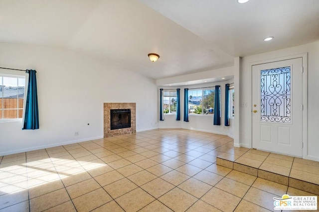 tiled entryway with a healthy amount of sunlight, vaulted ceiling, and a tiled fireplace