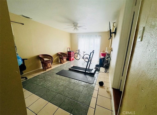 workout area with ceiling fan and light tile patterned floors